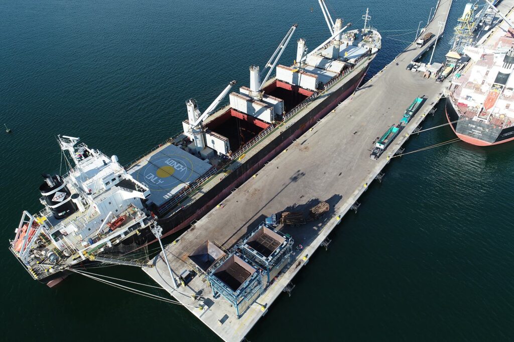 Buque atracado en el muelle durante el embarque de madera, vista aérea de día